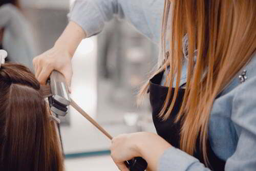 מעצבת שיער עושה ללקוחה החלקת קראטין לשיער במספרה