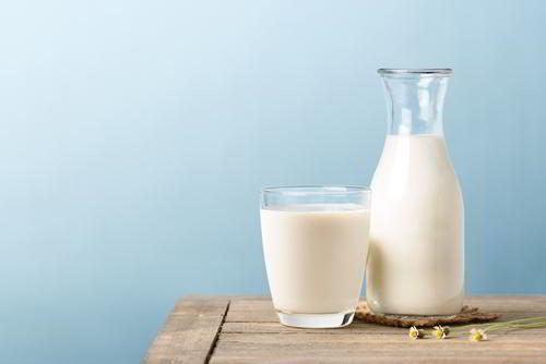 קנקן חלב וכוס חלב על שולחן עץ