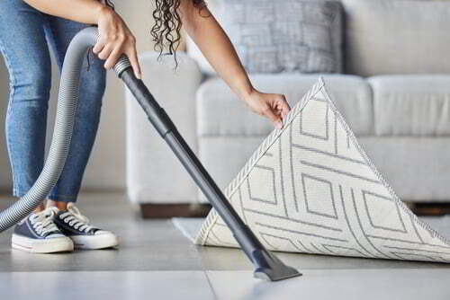 אישה מנקה את הרצפה עם שואב אבק