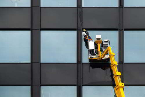 גבר על מנוף מנקה חלונות בניין בגובה